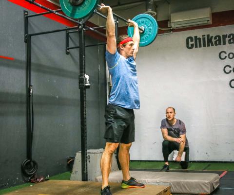 Mike performs thrusters with Guston judging